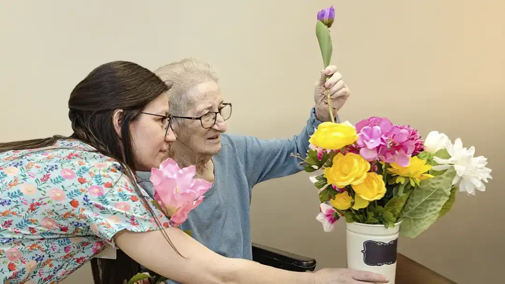 Caregiver and senior arranging colorful flowers